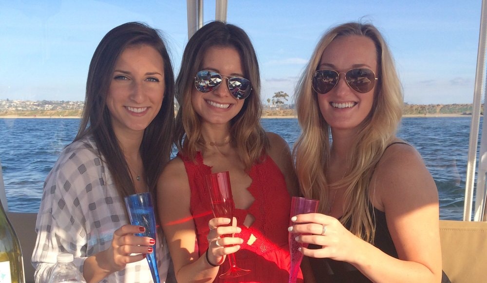 Three friends toasting with champagne glasses on a Duffy boat
